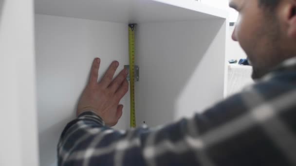 新しい完成したキッチン用の棚やキャビネットの組み立てを始めた空のアパートで 大工の測定棚 彼の周りには仕事の道具が — ストック動画