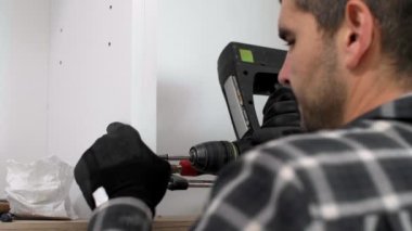 Marangoz duvardaki mutfak rafının montajını tamamlıyor..