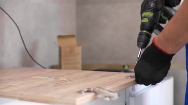 Marangoz mutfak raf kapısının mekanizmalarını (eklemlerini) kurar ve vidalar.