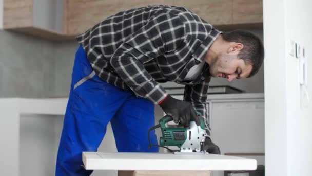 Seorang Tukang Kayu Dengan Jigsaw Corded Memotong Sebagian Dari Permukaan — Stok Video