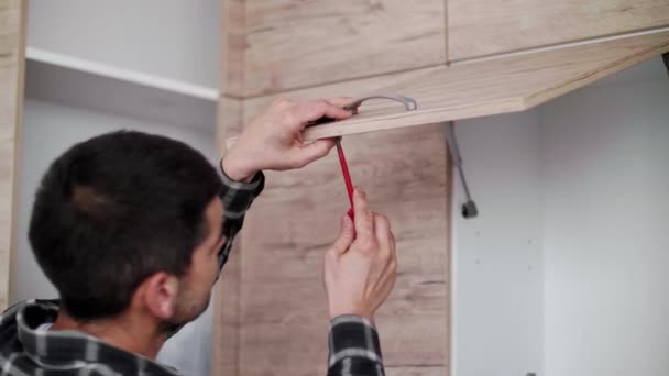 木匠把带有螺丝刀的手柄和螺丝放在支撑厨房的门上 — 图库视频影像