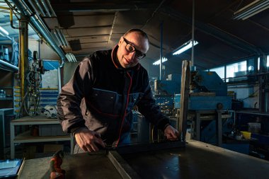 Metal çubuğu ölçen tamirci atölyede çalışıyor..