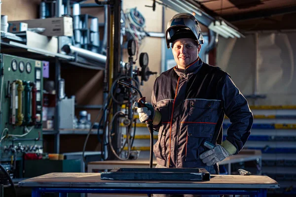 一个微笑的焊工在工厂的工作场所摆姿势的画像 很明显 这位大师正在从事焊接工作 — 图库照片