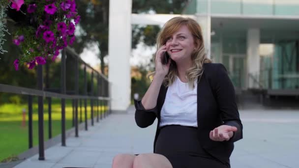 Усміхнена Біла Вагітна Бізнес Леді Сидить Сходах Перед Сучасною Архітектурою — стокове відео