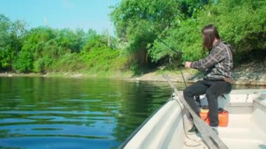 Nehir kıyısının yakınındaki sığ sularda beyaz teknede balık tutan orta yaşlı rahat bir adam. O, yüzen beyaz bir teknede ahşap bir tahtanın üzerinde oturuyor. Mısır ve solucanları yem olarak kullanıyor. Oltayı makaralı ve yüzen oltayla tutuyor..