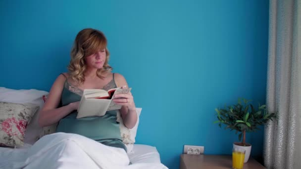 Egy Terhes Félig Ülő Helyzetben Ágyában Boldognak Tűnik Miközben Könyvet — Stock videók