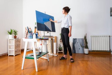 Genç, gülümseyen bir ressam kendi stüdyosundaki tuvale boya sürüyor. Etrafında resim yapmak için eşlik eden diğer malzemeler de görülebiliyordu. Bazı fotoğraflarda, bir elinde bir palet boya tutarken, diğer elinde de acı ile boyayı sürüyor.