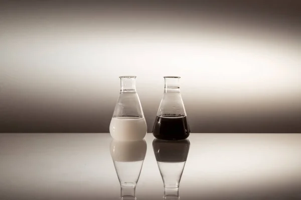 科学实验室的瓶中充满了反光表面的黑白液体 — 图库照片