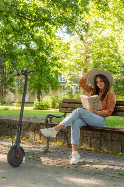 Молода Красива Дівчина Капелюхом Сидить Лавці Парку Читаючи Книгу Електричний — стокове фото