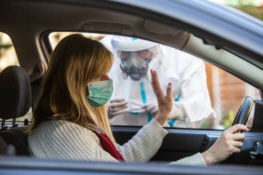 Kadın sürüş sırasında COVID 19 testi yapmayı reddediyor. Hastanın burnundan araba camından DNA örneği alıyor. PCR teşhisi koyuyor. Pasaportları var..