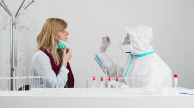 COVID-19 testi yapan bir tıp çalışanı hastanedeki kadın hastadan burun örneği Coronavirus için PCR testi, test kiti kullanan bir doktor..