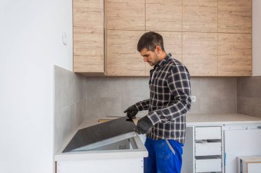 Marangoz, indüksiyon hobını mutfağın neredeyse bitmiş mutfağına yerleştirir..