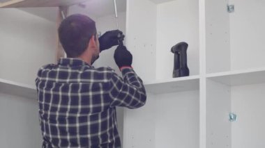 Marangoz mutfak raf kapısının mekanizmalarını (eklemlerini) kurar ve vidalar.