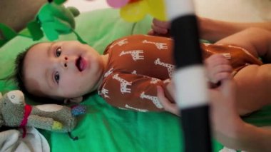 Anne oğlunu kaldırıyor, oturmasına yardım ediyor. Annem bebekle oynuyor. Oturmayı öğreniyor..