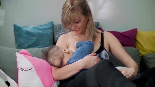 リビングルームでソファの上で母親の母乳育児赤ちゃん 母乳を食べる赤ん坊 — ストック動画