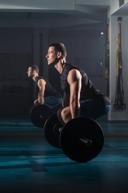 Antrenman yapan ve aynı zamanda spor salonunda kaldırma egzersizi yapan bir adam..