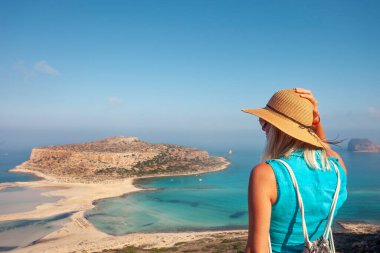 Hasır şapkalı turist kadın Girit adasındaki Balos sahilinin güzel Akdeniz manzarasına bakıyor..