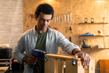 Marangoz atölyedeki küçük tahta bir sandıkta matkapla çalışıyor..