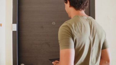 Evinin kapısında kucağında bebeği olan bir anne teslimatçı tarafından teslim edilen paketi alır..