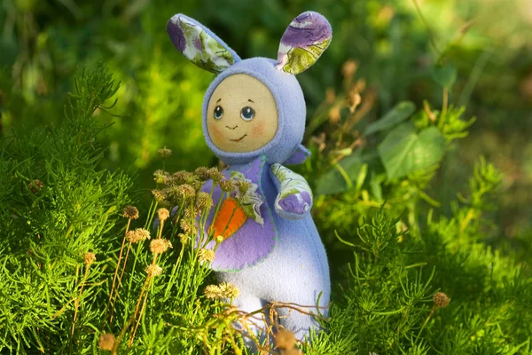 Positive toy hare among the bright greenery — Stock Photo, Image