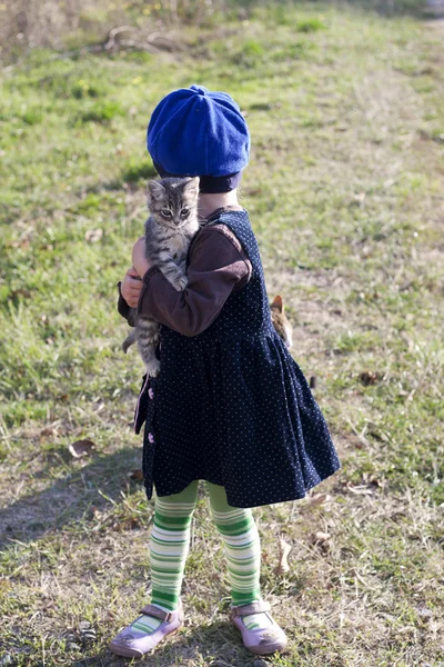 Fille dans une robe et prendre un petit chaton sur la main — Photo