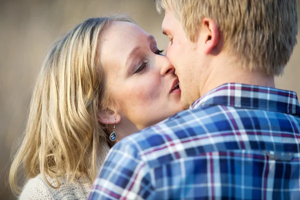 Joven pareja adulta besándose al aire libre durante el día — Foto de Stock