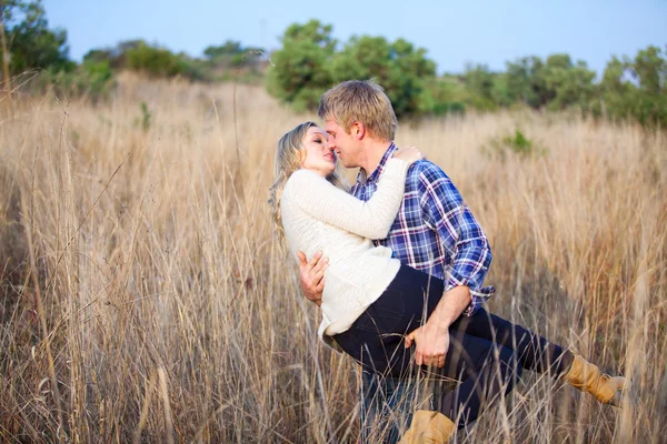 Giovane uomo scherzosamente raccogliendo la sua ragazza per un bacio — Foto Stock