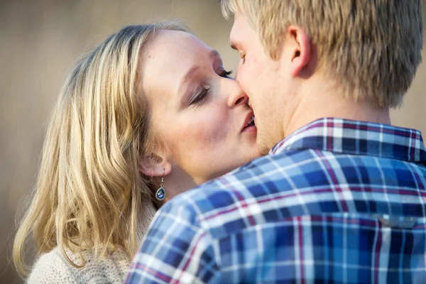 Jovem casal adulto beijando fora durante o dia Imagem De Stock