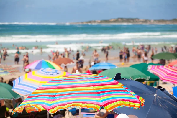 Cena de praia com guarda-chuvas coloridos e pessoas na praia — Fotografia de Stock
