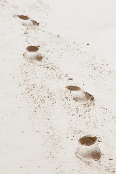 Cuatro huellas de un humano en la arena de la playa — Foto de Stock