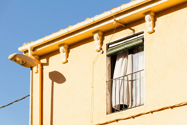 Open window with curtain on a sunny day in Spain. Yellow house type Spanish - Italian - French. South European architecture.