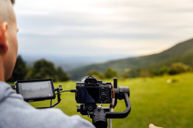 Dengeli bir kamera, sabit / sabit bir görüntü kaydediyor. Operatör kamerayı kullanırken fotoğraf arkadan ve yakından çekilmiş..