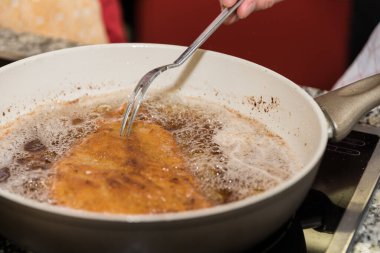 A cutlet is fried in a pan - prepare Wiener schnitzel clipart