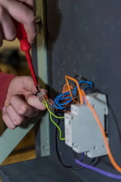 Skilled worker installs socket and relay with skilled worker tool - close up