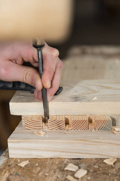 Carpenter works wood with chisel and mallet - craft close-up