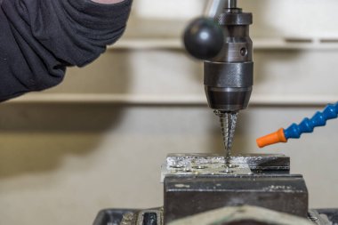 Metal endüstrisindeki yetenekli işçiler bir matkapla çalışıyorlar. Yakın plan.