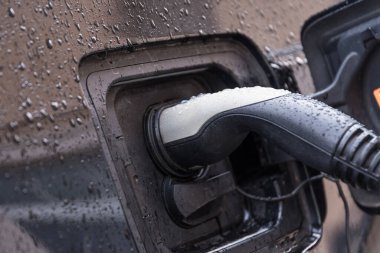 Şarj etmek için şarj istasyonuna bağlı elektrikli araba - şarj istasyonuna yakın çekim