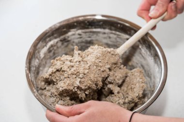 Ev yapımı çavdar ekmeği için hamuru ahşap kaşıkla karıştır. Yakın çekim.