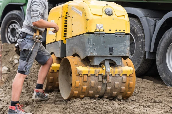 Construction worker works with trench roller on construction site - construction industry