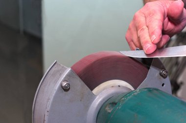 Zanaatkar bıçakları tekerlek öğütücüsüyle biler. Yakın plan.