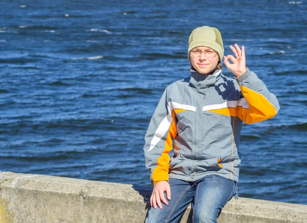 A boy sits and shows thumbs OK — Stock Photo, Image