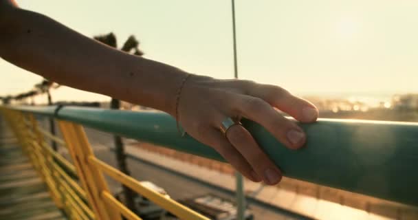 Mujeres de la mano deslizando la balaustrada del paseo marítimo en el sol puesta del sol haciendo bengalas — Vídeos de Stock