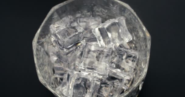 Kamera folgt Likörstrahl, während Getränk mit kaltem Eis ins Glas gegossen wird — Stockvideo