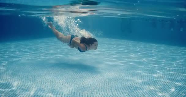 Krásné mladé ženy se ponoří do čisté modré vody v bazénu na dovolenou — Stock video