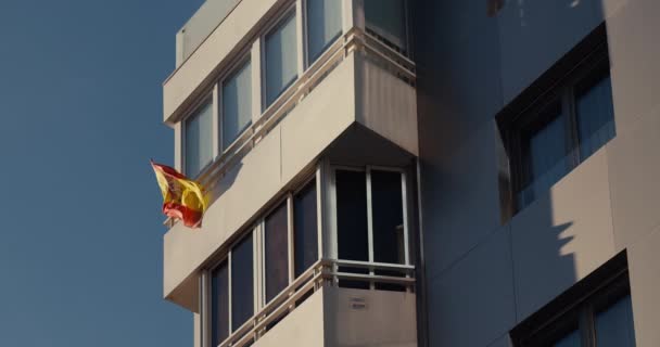 Viento ondeando mueve bandera española en la parte superior del edificio moderno en cámara lenta puesta de sol — Vídeos de Stock