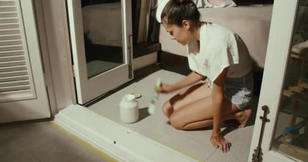Kobieta remontuje swój dom i maluje parapet białą farbą — Wideo stockowe