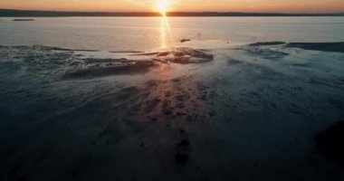 İnsansız hava aracı gün batımında Torrevieja 'nın doğal parkındaki bir gölün üzerinden ufukta uçuyor.
