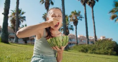 Güzel, genç esmer kadın güneşli yaz parkında karpuz yiyor.