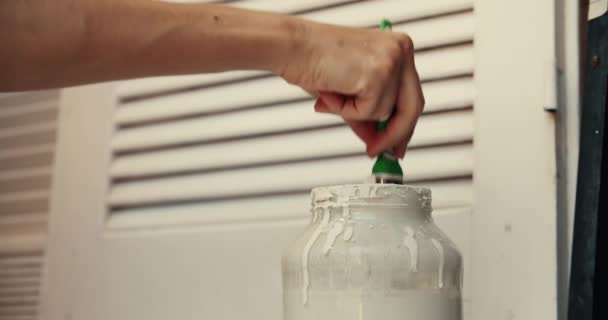 Womans mano de cerca sumergiendo el pincel en botella y pinta la persiana de madera — Vídeo de stock