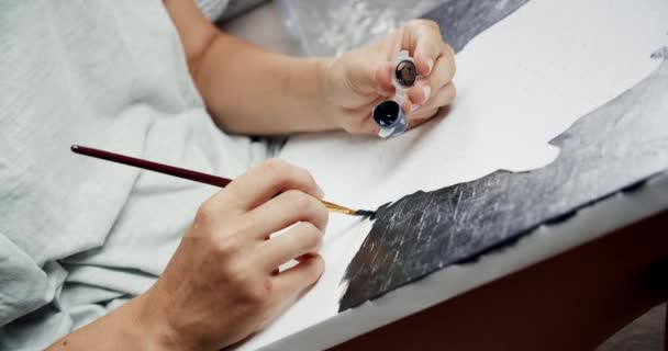 Femei mâini aproape de desen cu pensulă de vopsea și vopsea neagră pe pânză albă — Videoclip de stoc